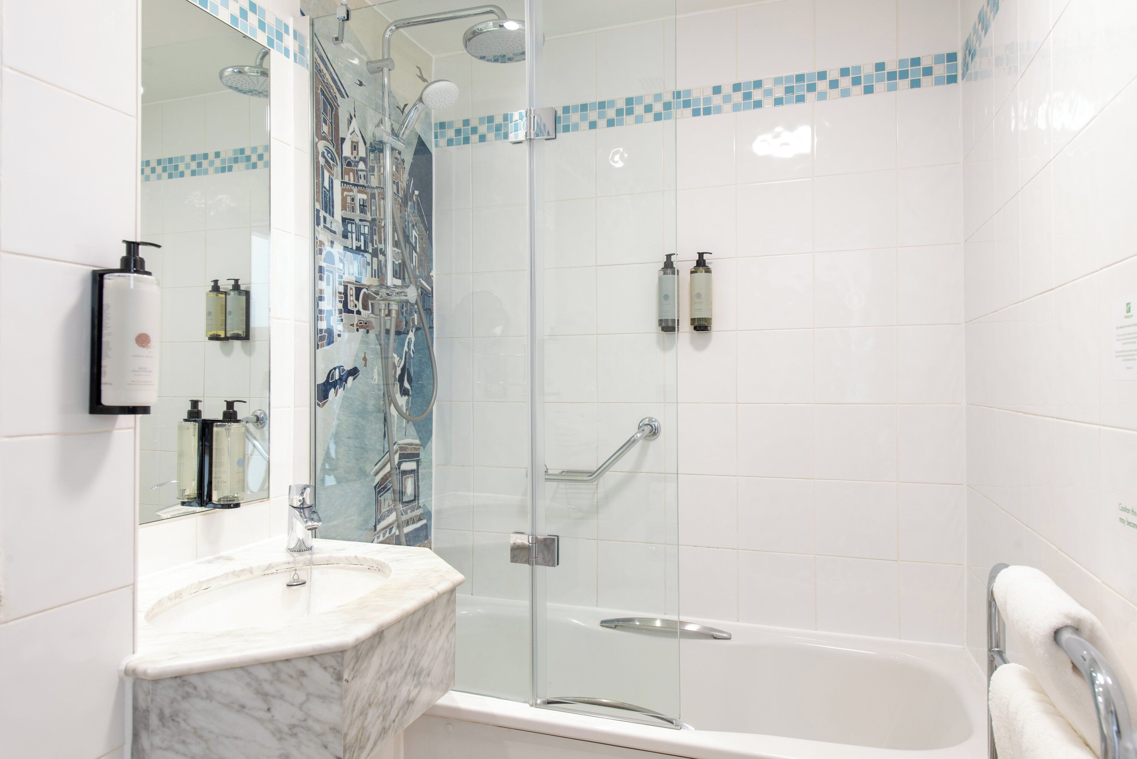 A bathroom with a glass-enclosed shower, a marble sink, and a white bathtub.