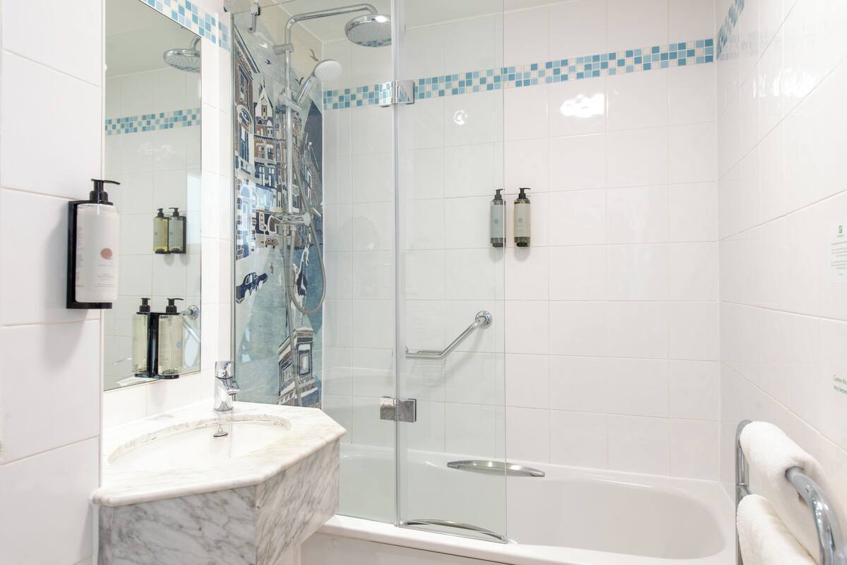 Une salle de bain avec une douche à parois de verre, un lavabo en marbre et une baignoire blanche.