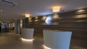 A reception area with a modern design, featuring a wooden wall with a neon sign and two illuminated reception desks.