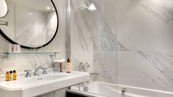 A modern bathroom with a white marble sink, a glass-enclosed shower, and a large mirror.