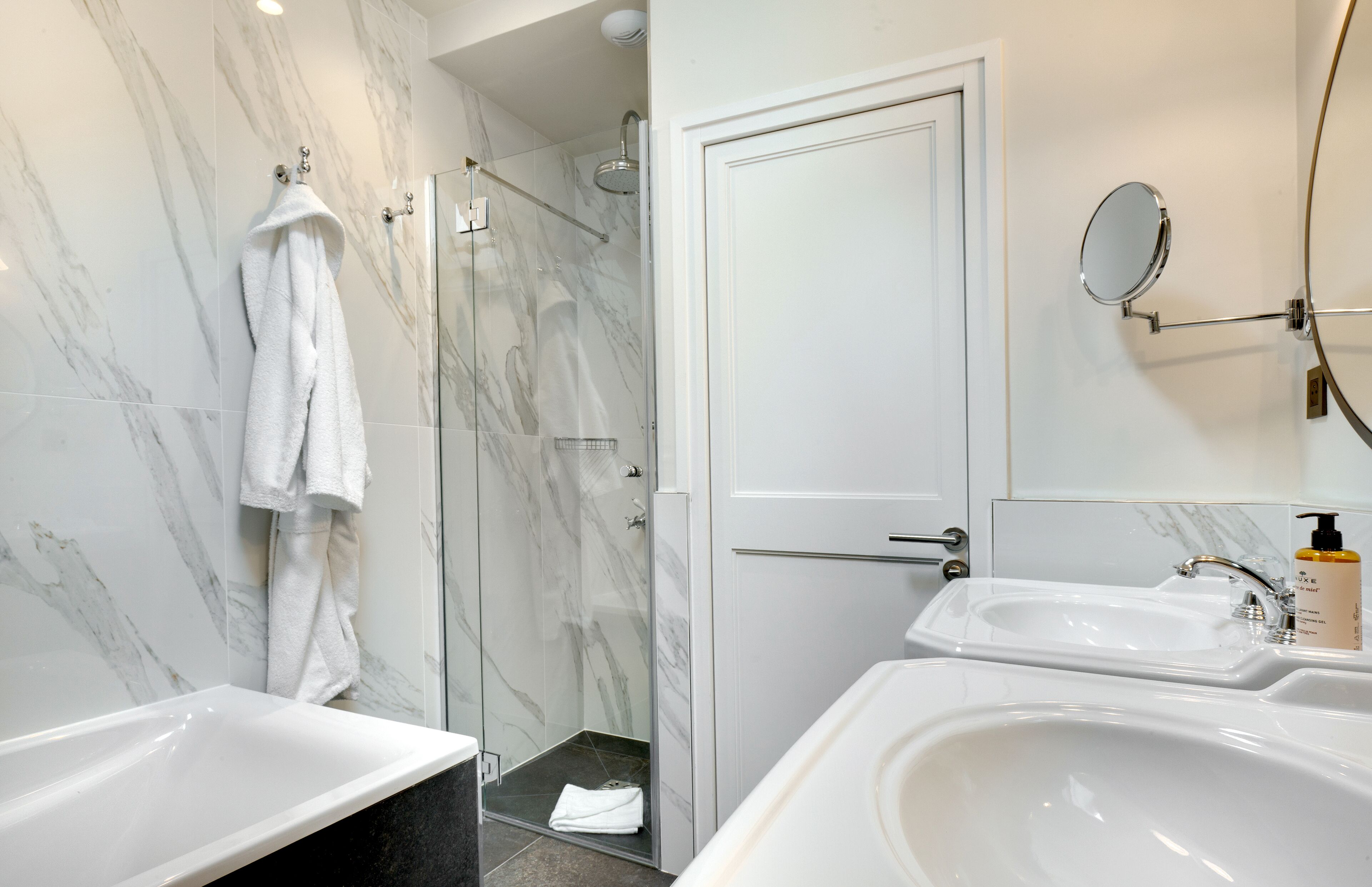 Un baño moderno con ducha envuelta en vidrio, una bañera blanca y un lavamanos con espejo.
