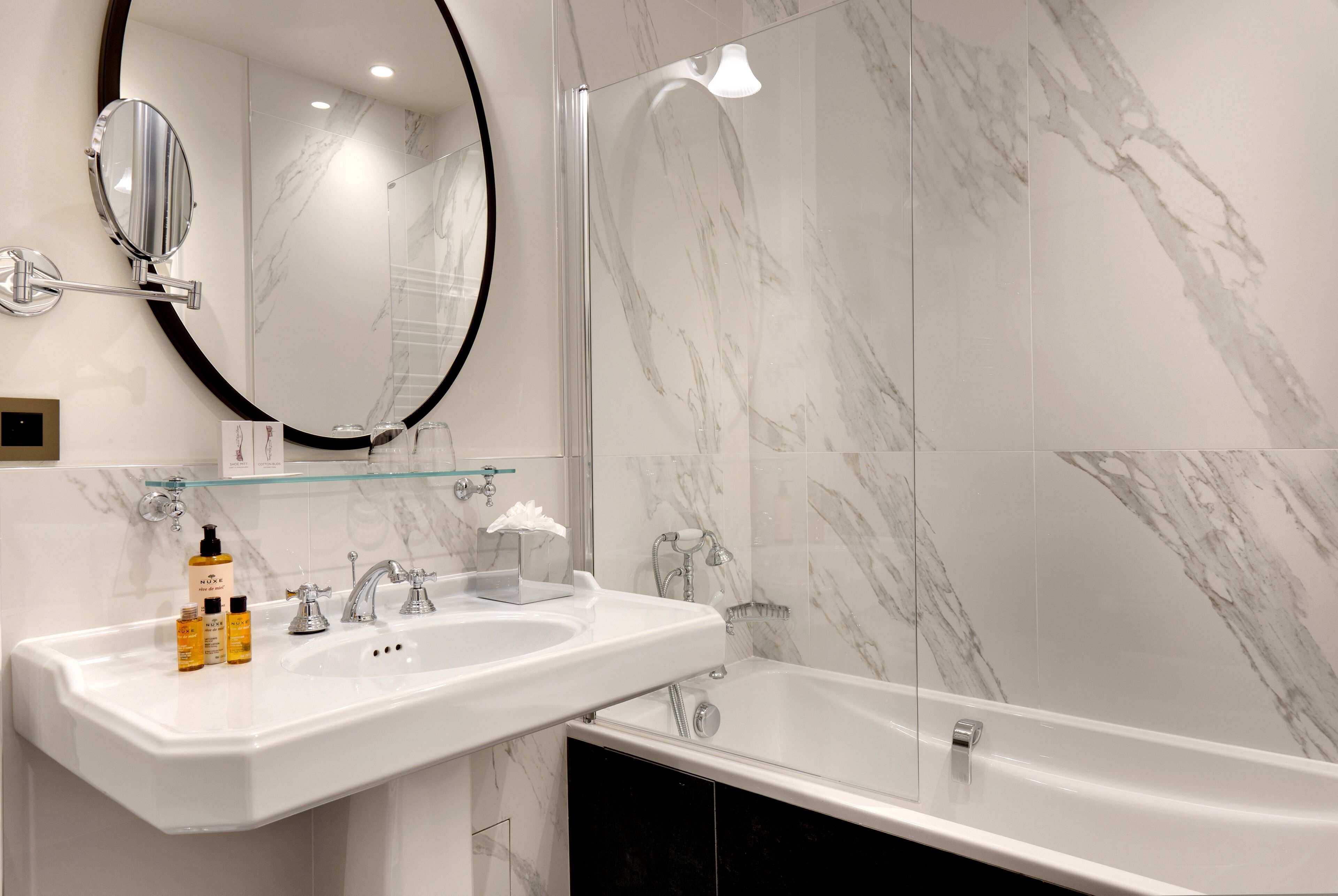 A modern bathroom with a white sink, mirror, and bathtub.