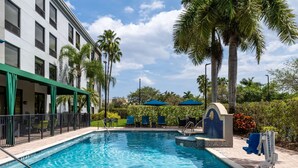 A swimming pool with a tiled edge, a lifeguard stand, and lounge chairs. - Hampton Inn West Palm Beach Florida Turnpike (West Palm Beach)