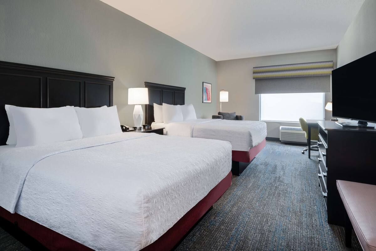 Een hotelkamer met twee bedden, een bureau, een televisie en een raam met uitzicht.