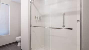 A modern bathroom with a glass-enclosed shower, a toilet, and a window with blinds.
