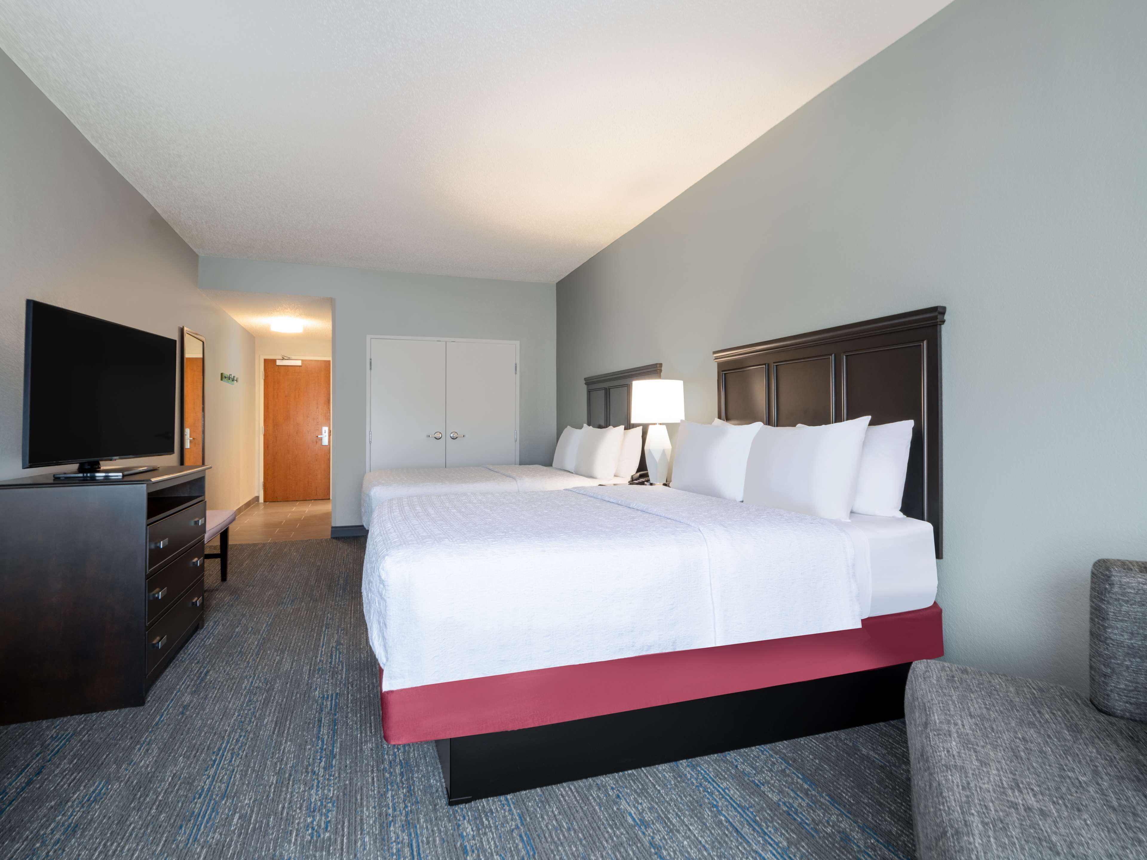 A hotel room with a bed, a TV, a desk, and a chair.
