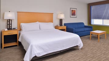 Une chambre d’hôtel avec un lit, deux tables de chevet, une chaise, une petite table et une fenêtre.