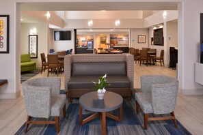 Relax in the hotel's inviting lobby, featuring a cozy seating area with a sofa and armchairs, a round table, and a flat-screen TV.