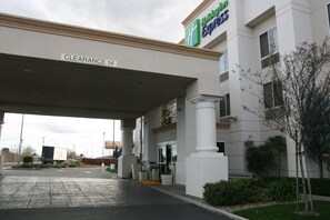 A Holiday Inn Express with a clearway sign overhead, a paved parking area, and a building with a modern facade. - Holiday Inn Express Stockton Southeast by IHG (Stockton)