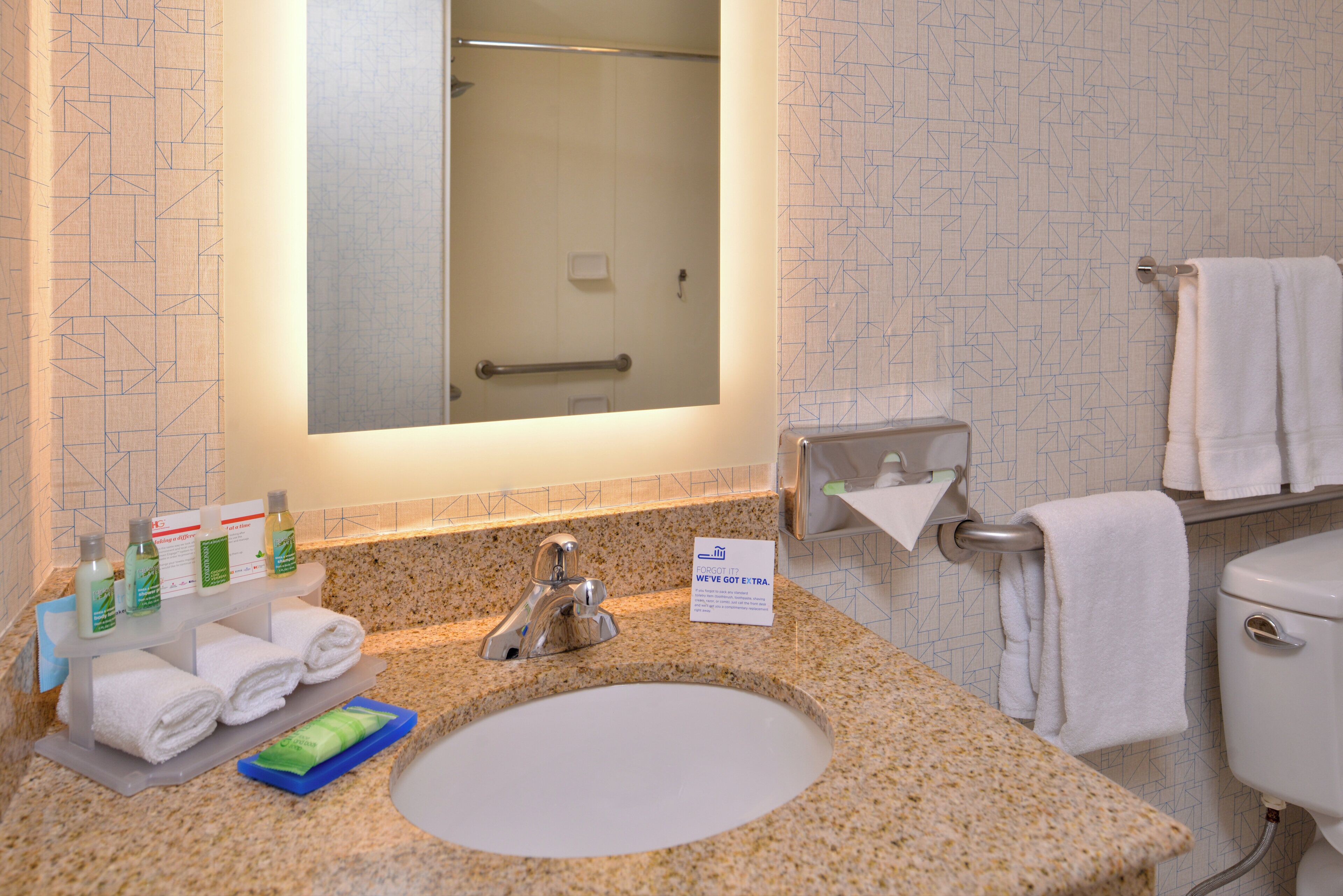 A bathroom with a sink, mirror, towel rack, and toiletries.