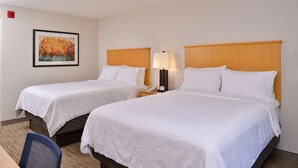 Two single beds with wooden headboards, a nightstand with a lamp, a framed picture on the wall, and a desk with a chair. - Holiday Inn Express Stockton Southeast by IHG (Stockton)