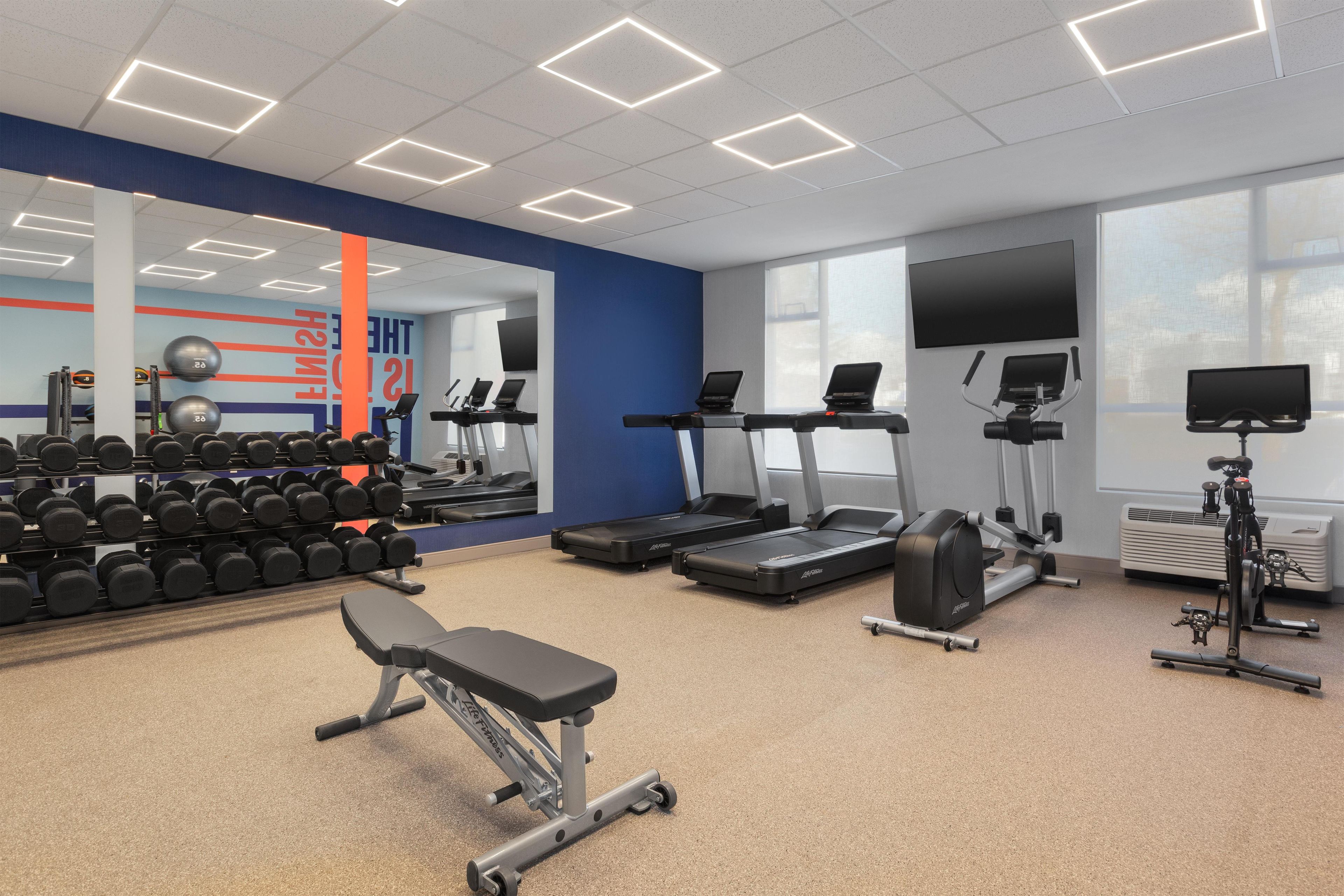 Un gimnasio con cintas de correr, mancuernas y equipo de ejercicio.