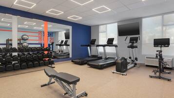 Un gimnasio con cintas de correr, mancuernas y equipo de ejercicio.