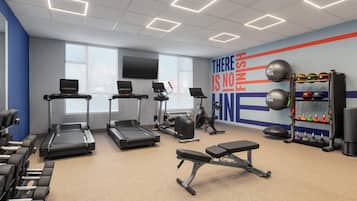 Ein Fitnessstudio mit Laufbändern, Gewichten und einer Wand mit motivierenden Sprüchen.