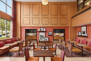 Enjoy meals in a warm and inviting dining area with round tables and cushioned benches.