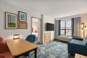 A hotel room with a bed, a desk, a chair, a dresser, a TV, and a large window with curtains. - Hampton Inn & Suites by Hilton Langley-Surrey (Surrey)