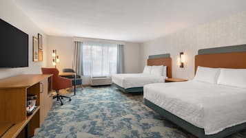 Une chambre d’hôtel avec deux lits, un bureau, une chaise, une télévision et une fenêtre avec des rideaux.
