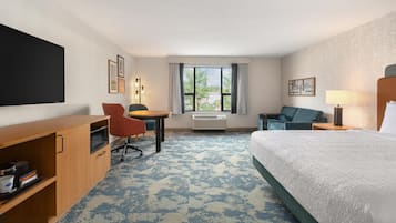Ein Hotelzimmer mit einem Bett, einem Schreibtisch, einem Stuhl, einem Fernseher und einem Fenster mit Vorhängen.