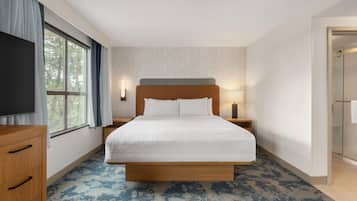 Ein Hotelzimmer mit einem großen Bett, einem Holzschrank, einem Fernseher und einem Fenster mit Vorhängen.