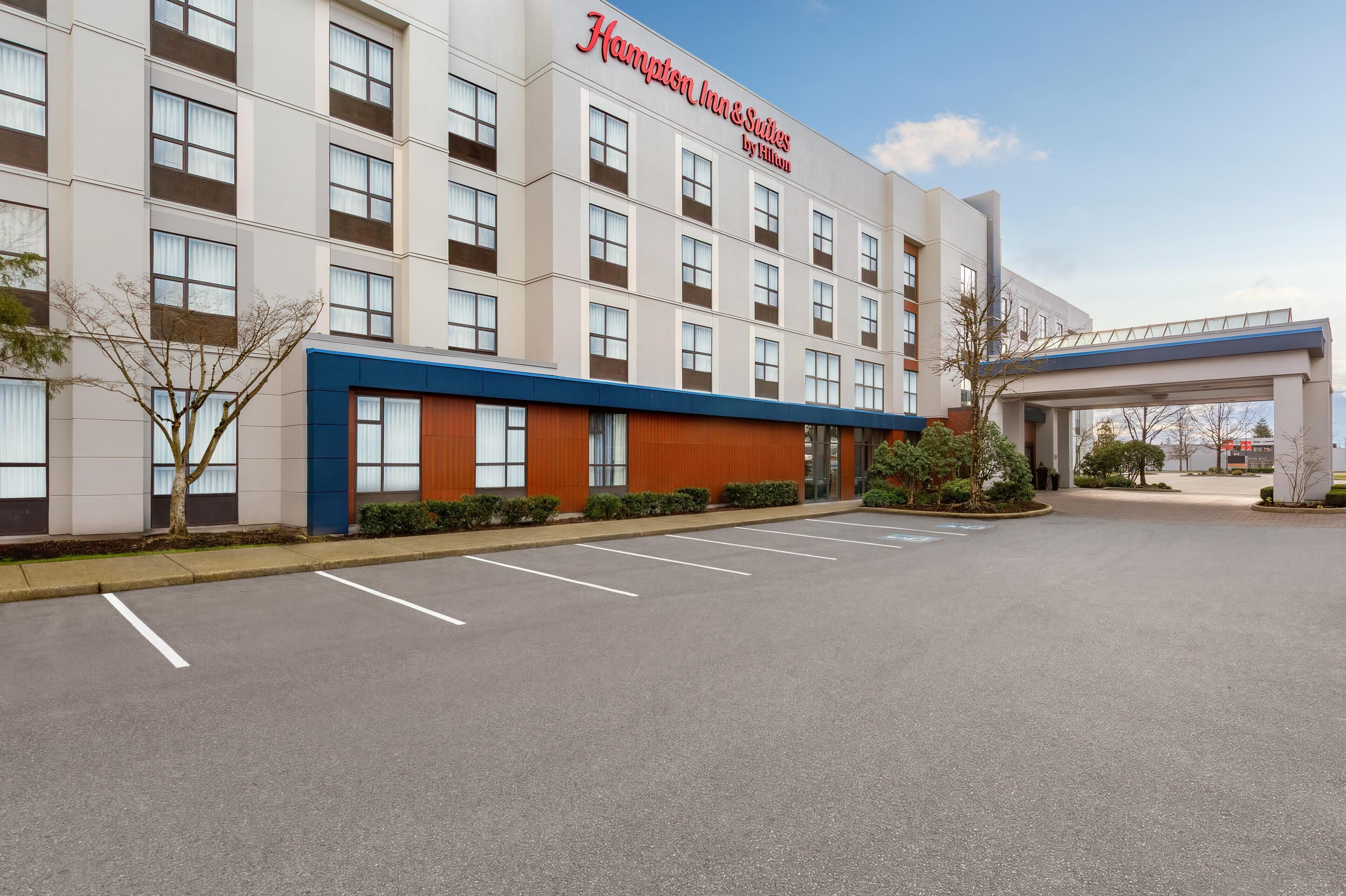 A Hampton Inn & Suites by Hilton building with a parking lot and a covered walkway.