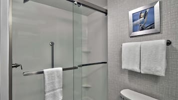 Un baño moderno con cabina de ducha de vidrio, un inodoro y dos toallas colgadas en un perchero.