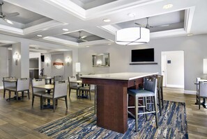 A modern hotel lobby with a bar area, seating, and a television mounted on the wall. - Hampton Inn Ft. Lauderdale Airport North Cruise Port (Fort Lauderdale)