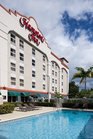 A Hampton Inn hotel with a swimming pool, lounge chairs, and a palm tree. - Hampton Inn Ft. Lauderdale Airport North Cruise Port (Fort Lauderdale)