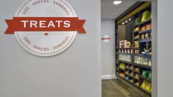 Un letrero en la pared con la palabra 'TREATS' y un logotipo circular que dice 'SIPS • SNACKS • SUNDRIES'.