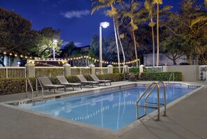 Una piscina al aire libre, sombrillas, sillones reclinables de piscina