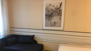 A room with a dark sofa, a bed with white bedding, and a framed artwork on the wall. - AltDüsseldorf (Düsseldorf)
