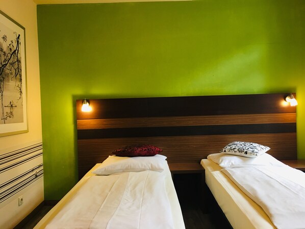 Una habitación con dos camas individuales, cada una con almohada y lámpara de noche.