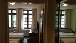 A hotel room with two beds, a desk, a chair, a mirror, and a window with curtains. - AltDüsseldorf (Düsseldorf)