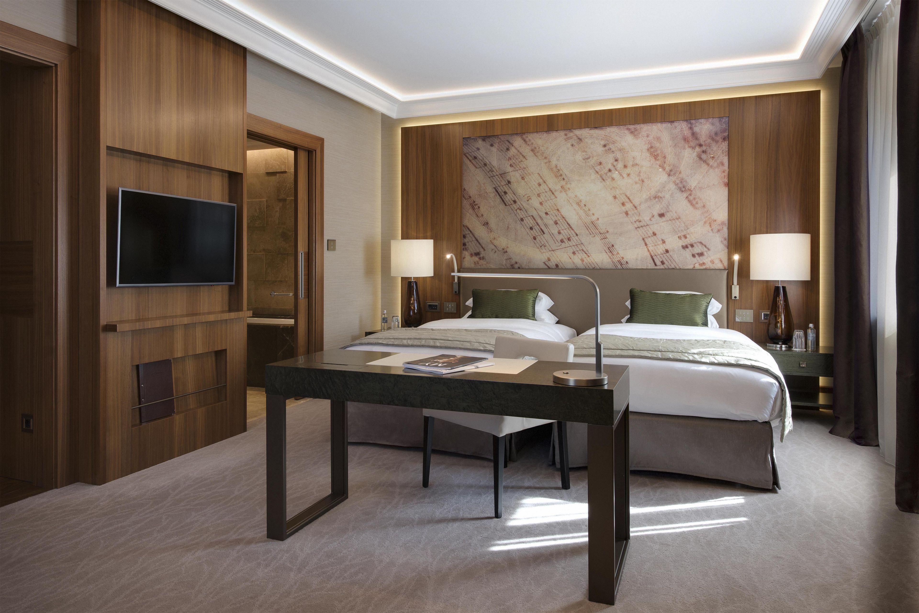 Habitació d'hotel amb un llit, taules de nit, televisió de pantalla plana i un mural gran a la paret.