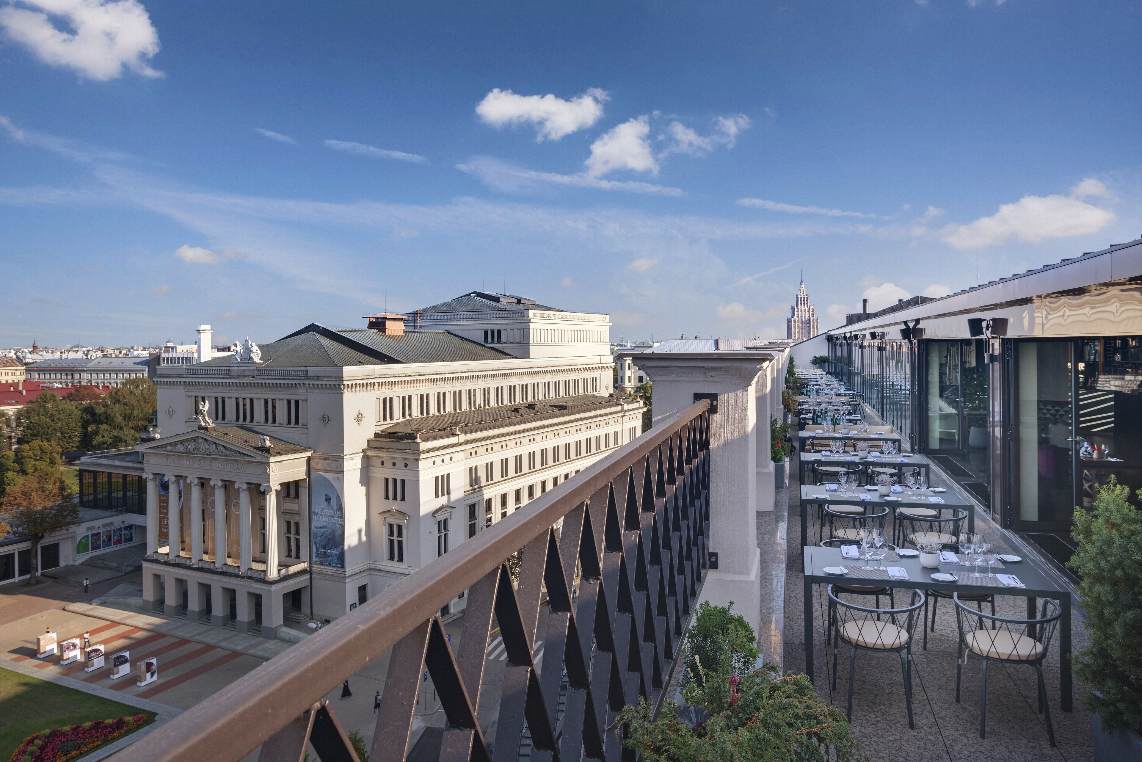 Un restaurante con terraza al aire libre que ofrece vistas a un edificio clásico con columnas y una cúpula.