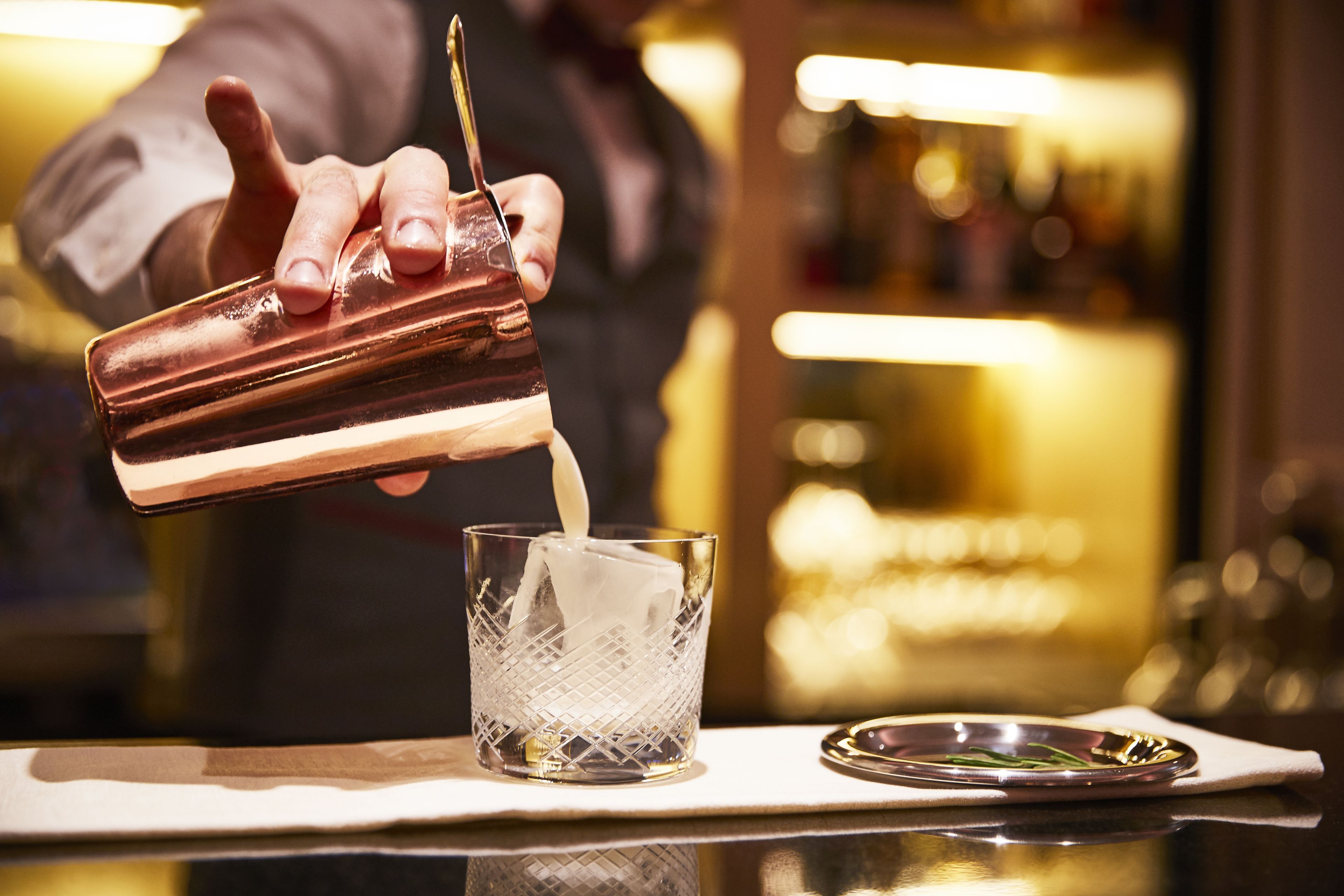 Ein Barkeeper gießt ein Getränk ein.