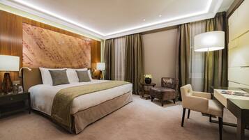 Habitación de hotel con una cama grande, dos mesitas de noche con lámparas, un escritorio con una silla y un panel decorativo en la pared.