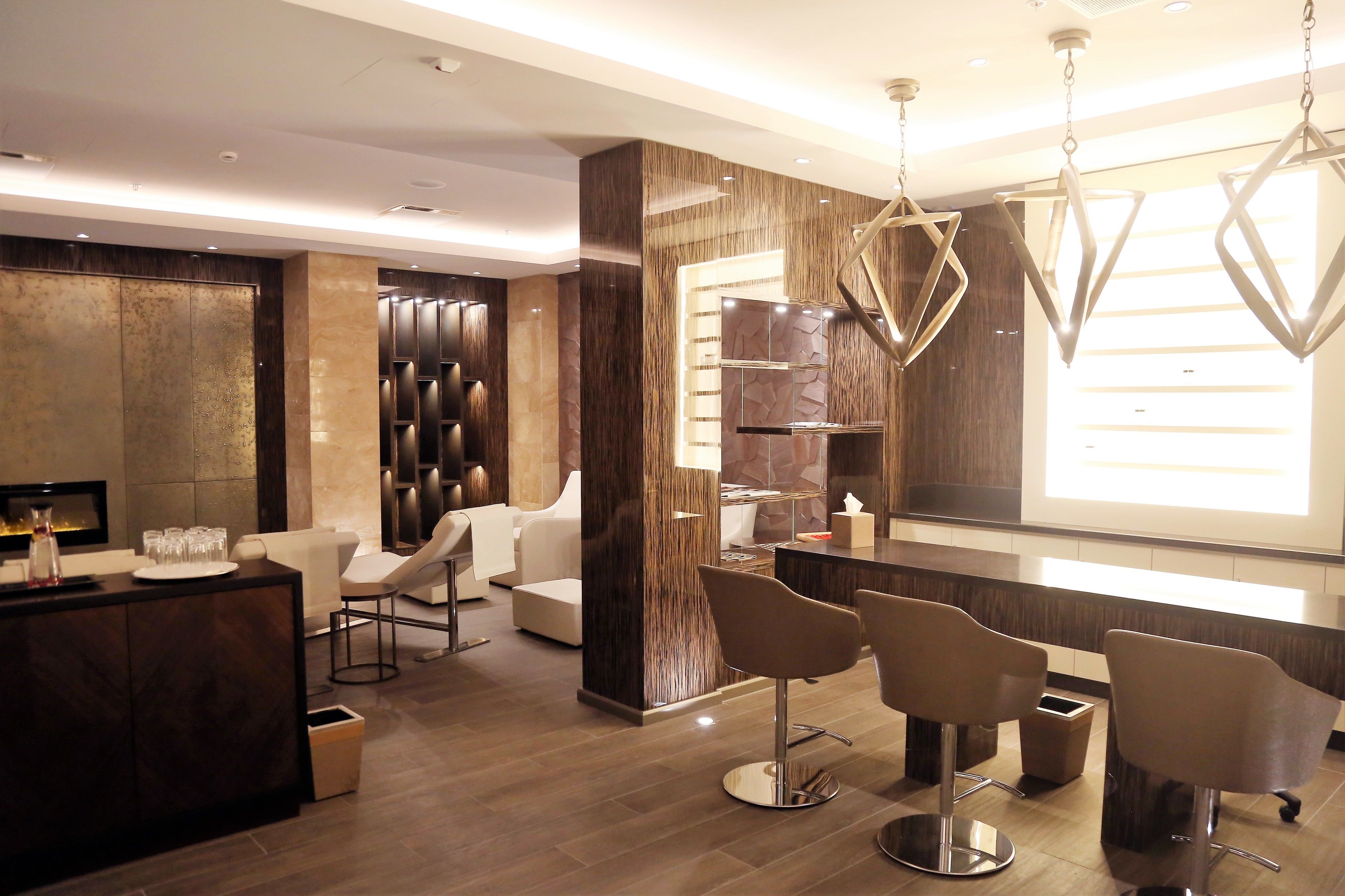 A modern bar area with a counter, bar stools, and a large window providing natural light.