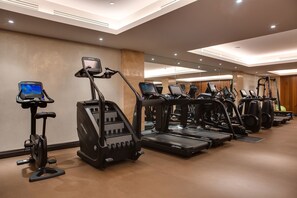 A gym with multiple treadmills, ellipticals, and exercise bikes, equipped with digital screens. - Grand Hotel Kempinski Riga (Riga)