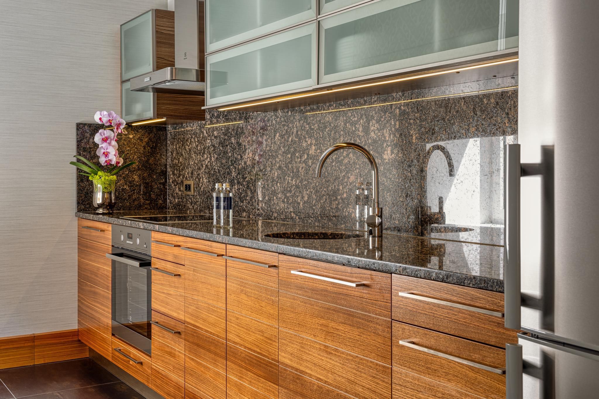 Una cocina moderna con encimera de granito, electrodomésticos de acero inoxidable y armarios de madera.