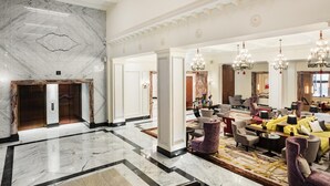 A spacious lobby with a marble floor, a reception desk, and multiple seating areas.