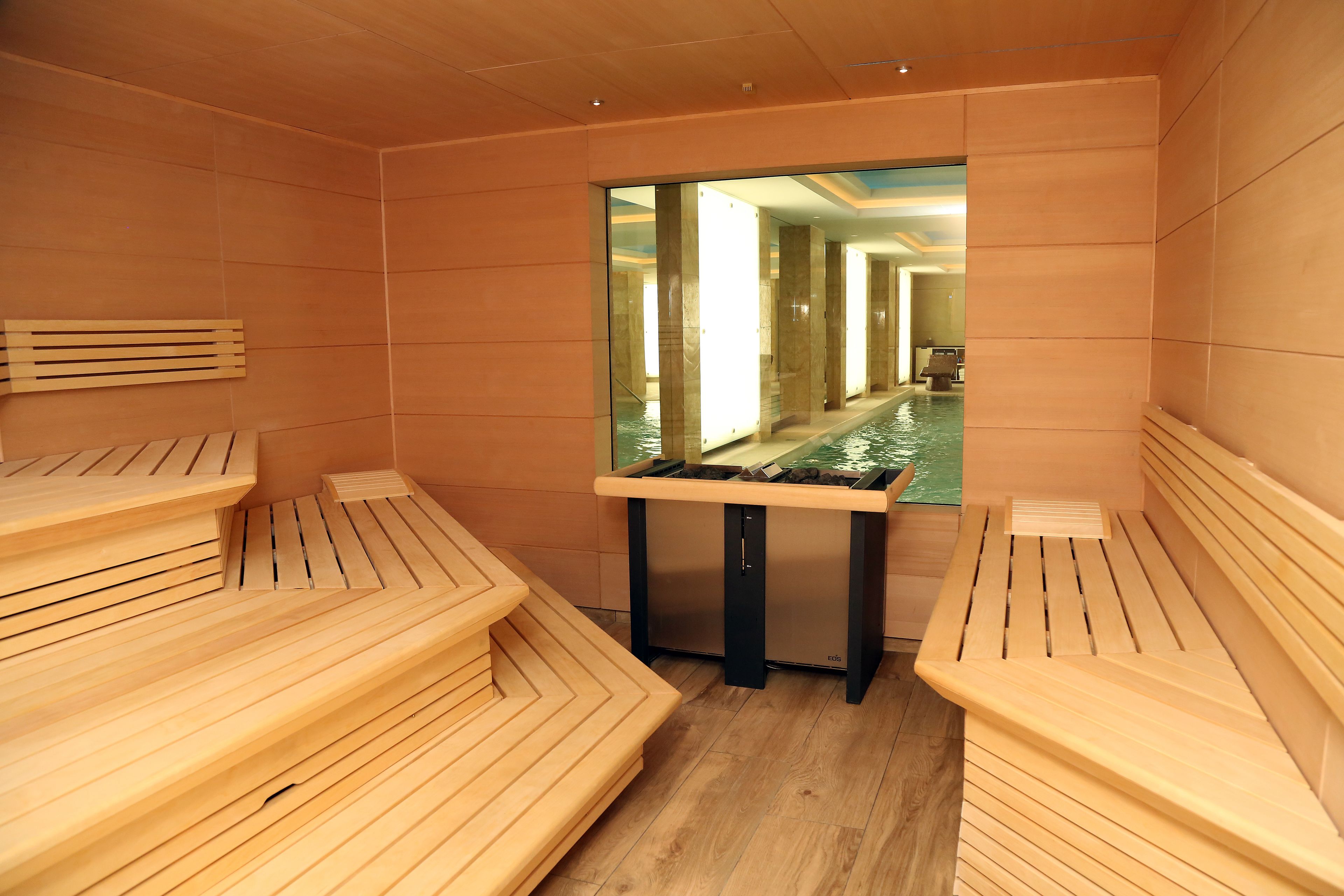 A sauna with wooden benches and a glass partition.