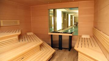A sauna with wooden benches and a glass partition.