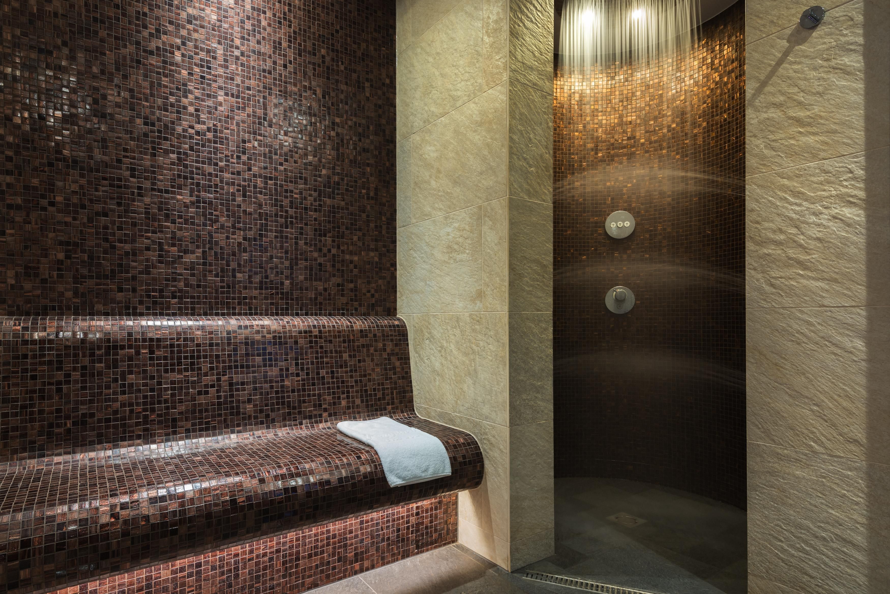 Un área de spa con un banco empedrado y una ducha con pared texturizada.