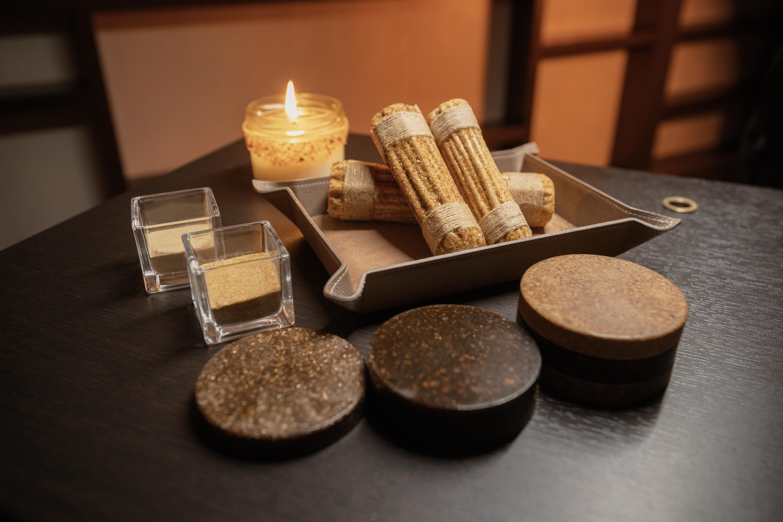 Una mesa con una vela, corchos y pequeños recipientes.