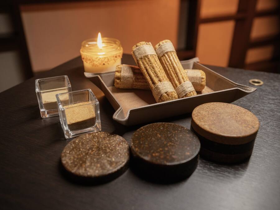 Una mesa con una vela, corchos y pequeños recipientes.