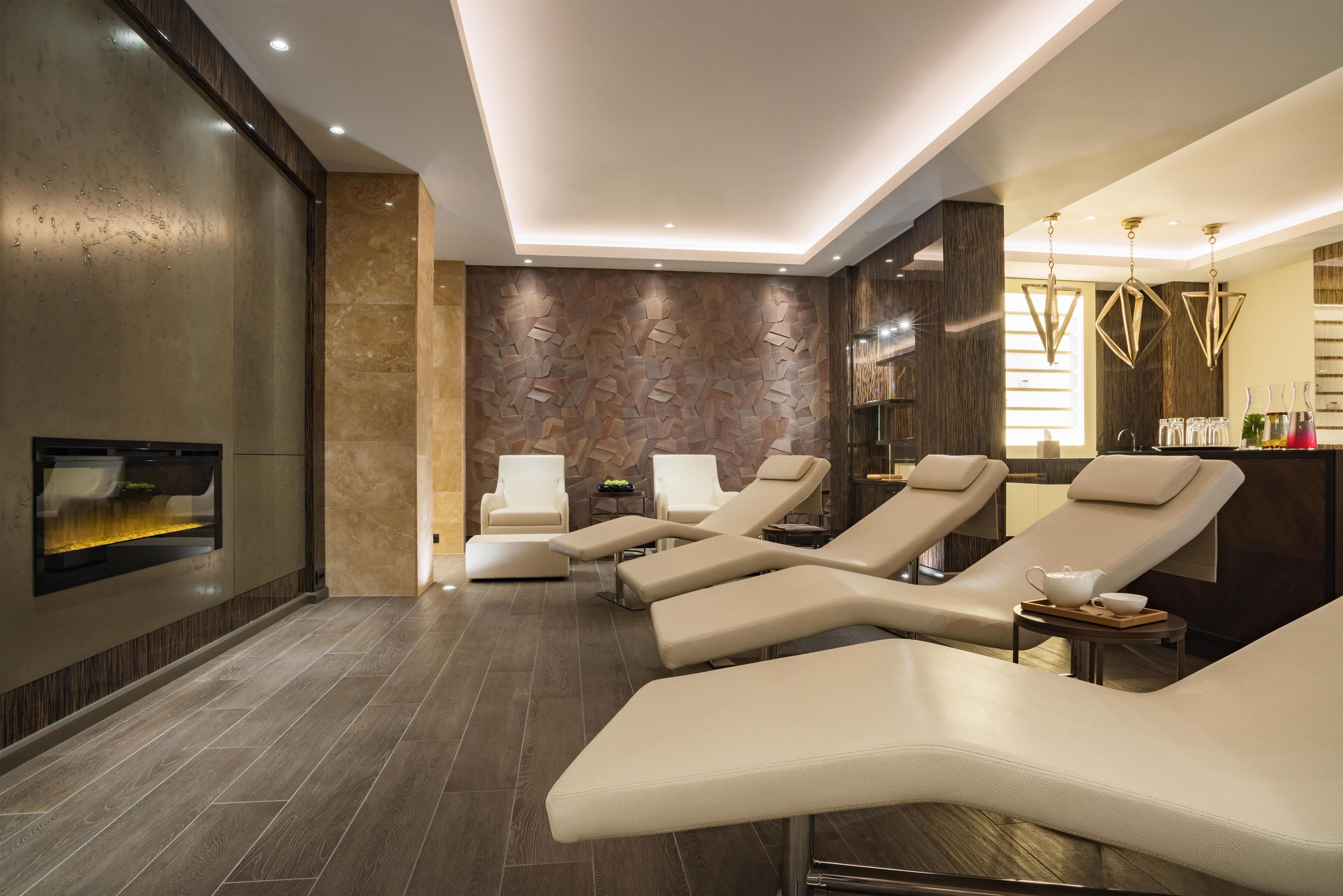 Un moderno spa con sillones reclinables, un televisor en la pared y una pared con textura de madera.