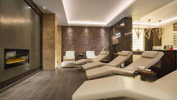Un moderno spa con sillones reclinables, un televisor en la pared y una pared con textura de madera.