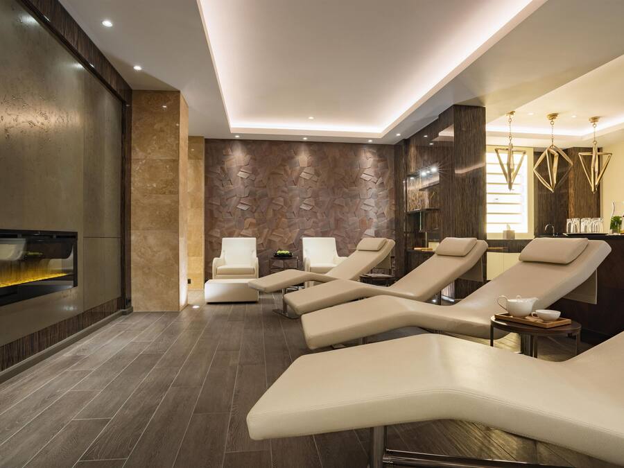 Un moderno spa con sillones reclinables, un televisor en la pared y una pared con textura de madera.
