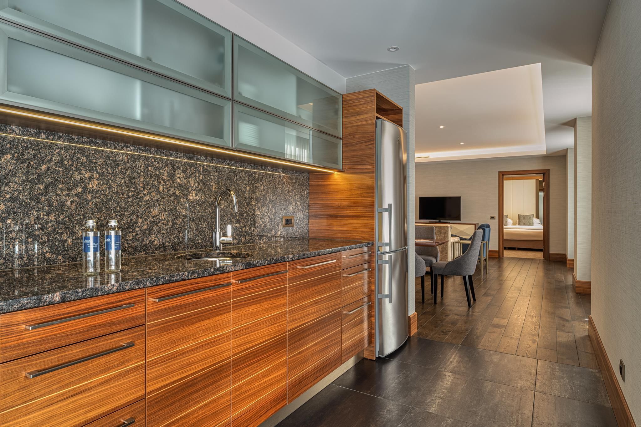 Eine moderne Küche mit Granit Arbeitsplatten, Holzschränken und einem Edelstahlkühlschrank.