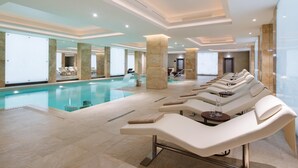 Un área de piscina interior moderna con sillones de descanso y vistas despejadas a la piscina.